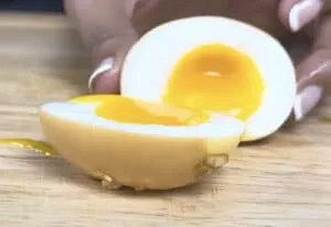 Half-boiled egg with runny yolk on a wooden surface, perfect for breakfast or ramen.